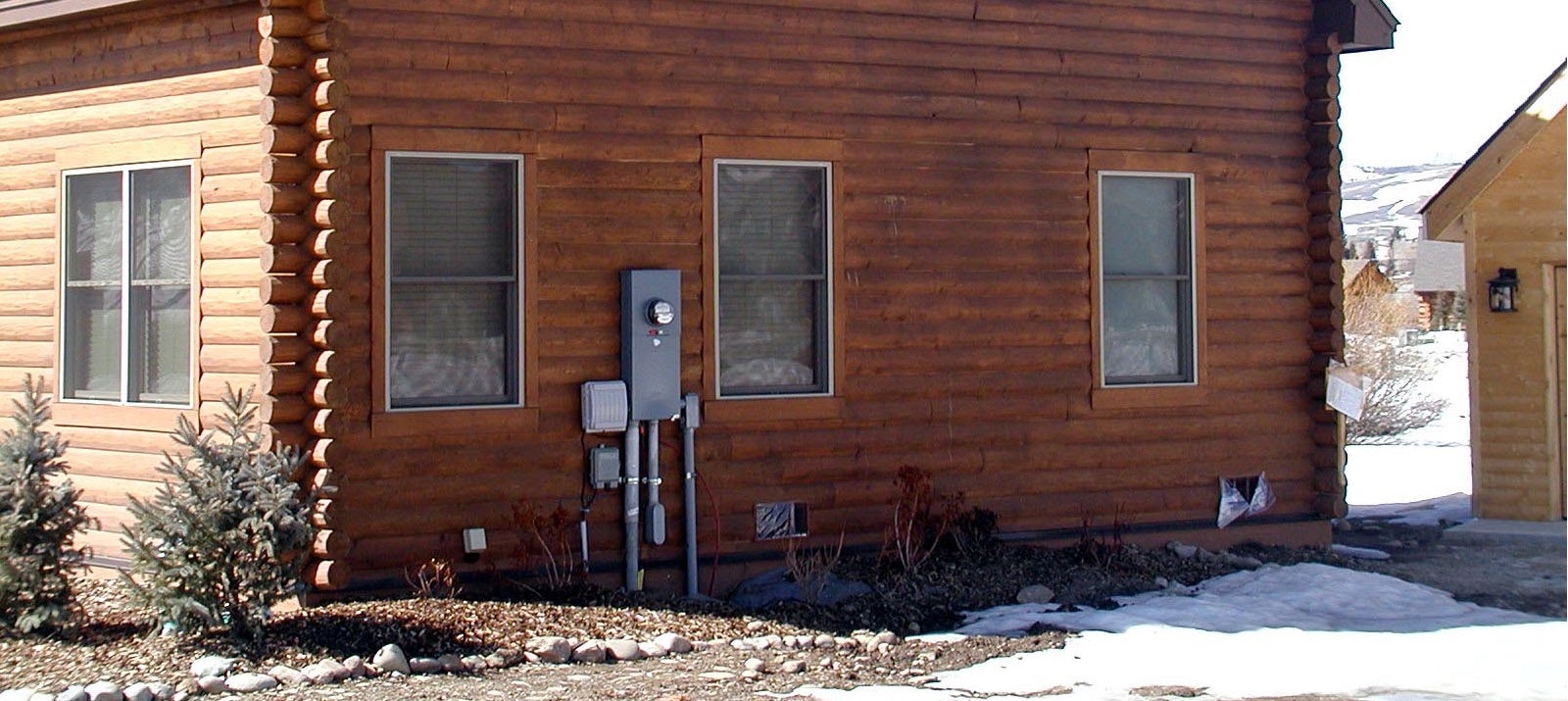 log house with electric meter attached to siding